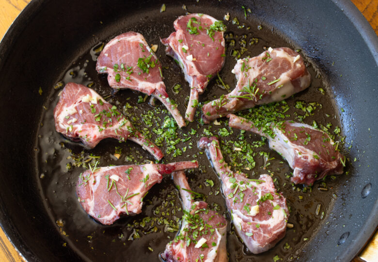 Lamb chops placed in a circular pattern in a large skillet.