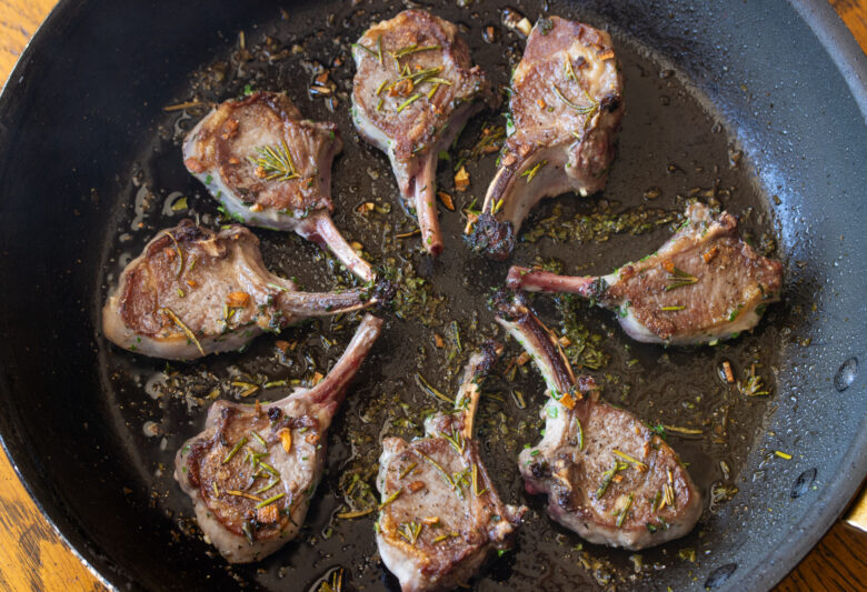Grilled lamb chops fully cooked in a large skillet.