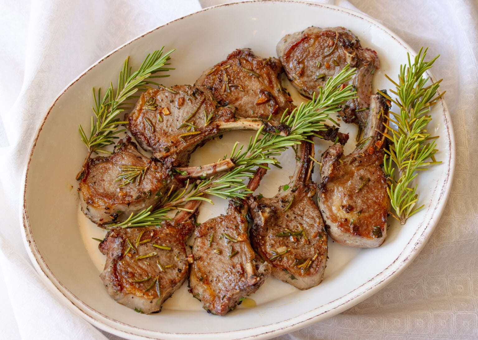 Grilled lamb chops served in an oval cream colored plate.
