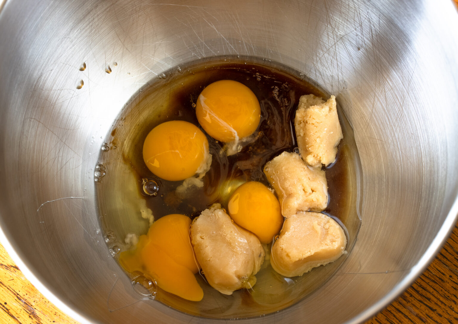 Heavy cream, eggs, almond paste in a bowl to be mixed together.