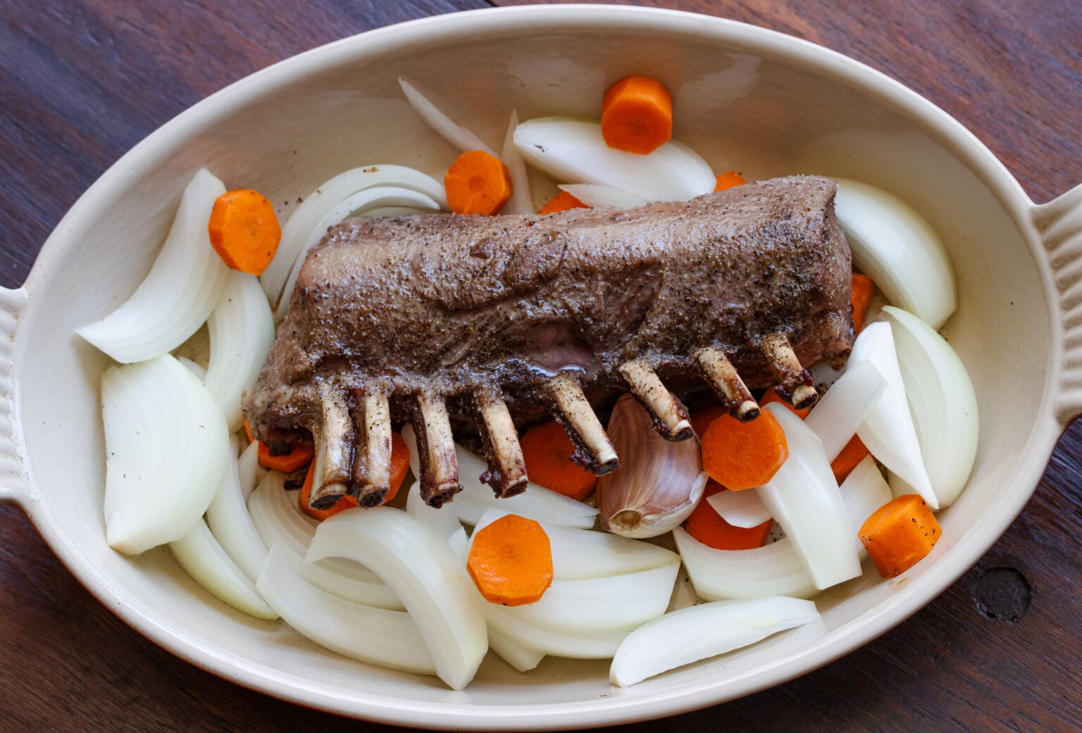 Lamb in the roasting pan surrounded by the onion, carrot adn garlic ready to go back in th oven for the final roasting.