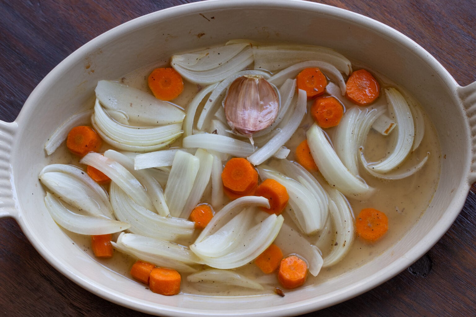 Adding white wine to the onion and carrots and reducing the sauce.