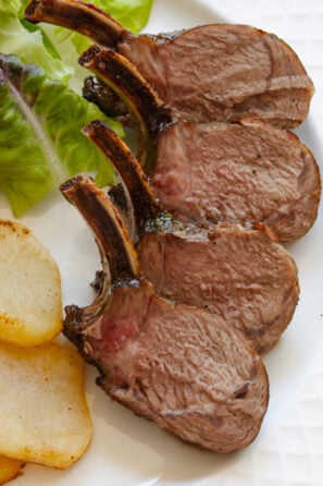 Roasted rack of lamb with caramelized crust served on. a white plate.