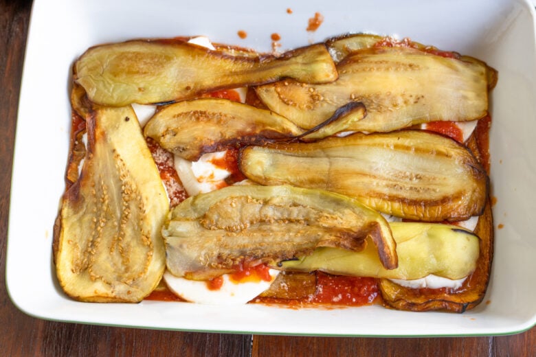 Layers of tomato, eggplant and cheese placed on a oven proof baking dish.