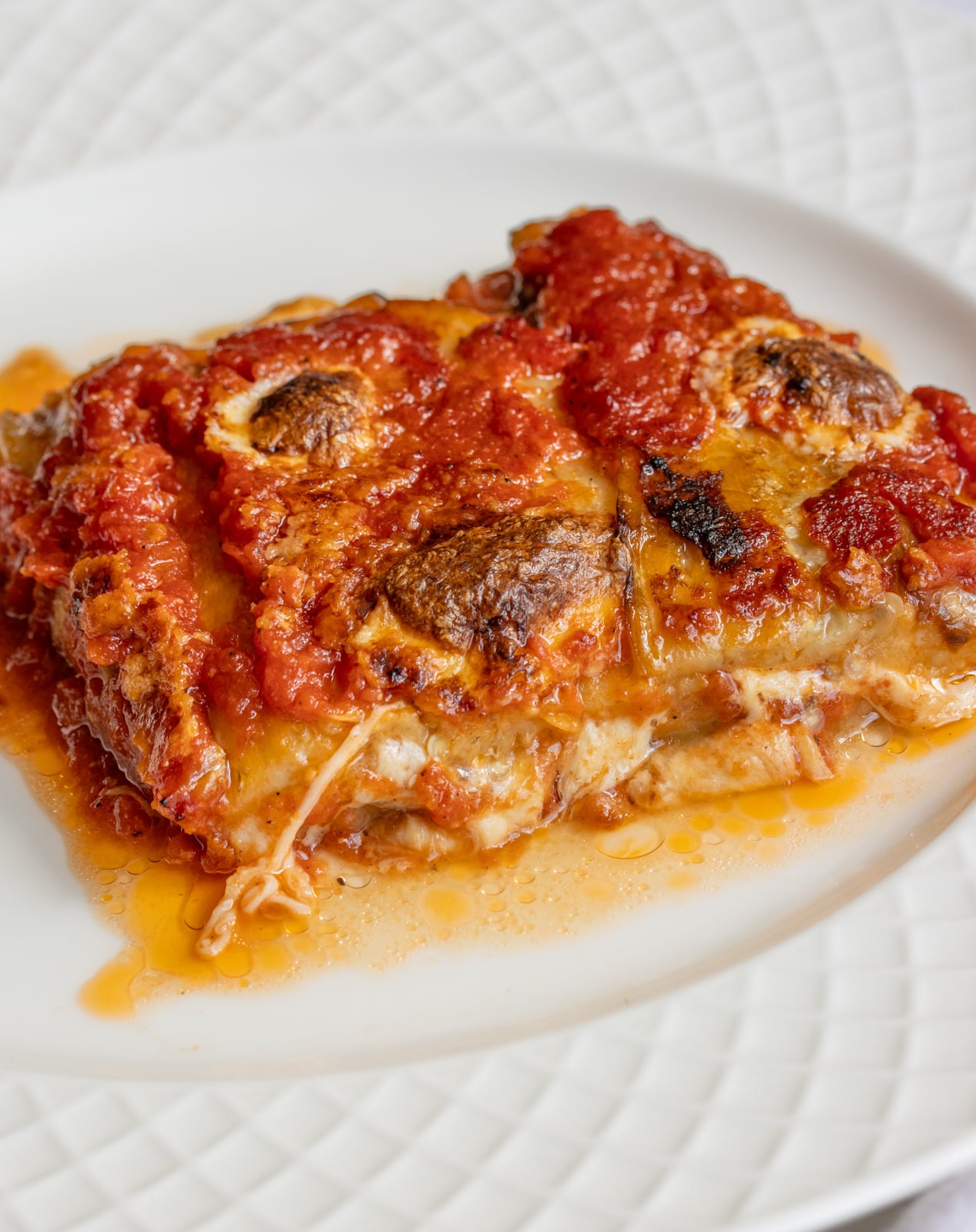 Eggplant Parmigiana portion on a lattice white plate.