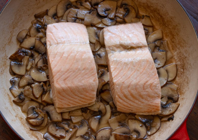 Steamed salmon ready to be removed from the skillet.