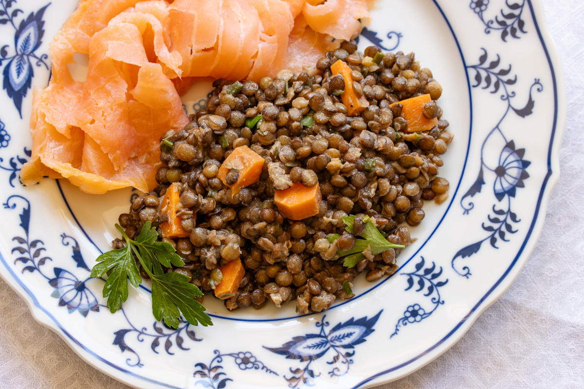 Lentil salad served with smoked salmon in white and blue plate.