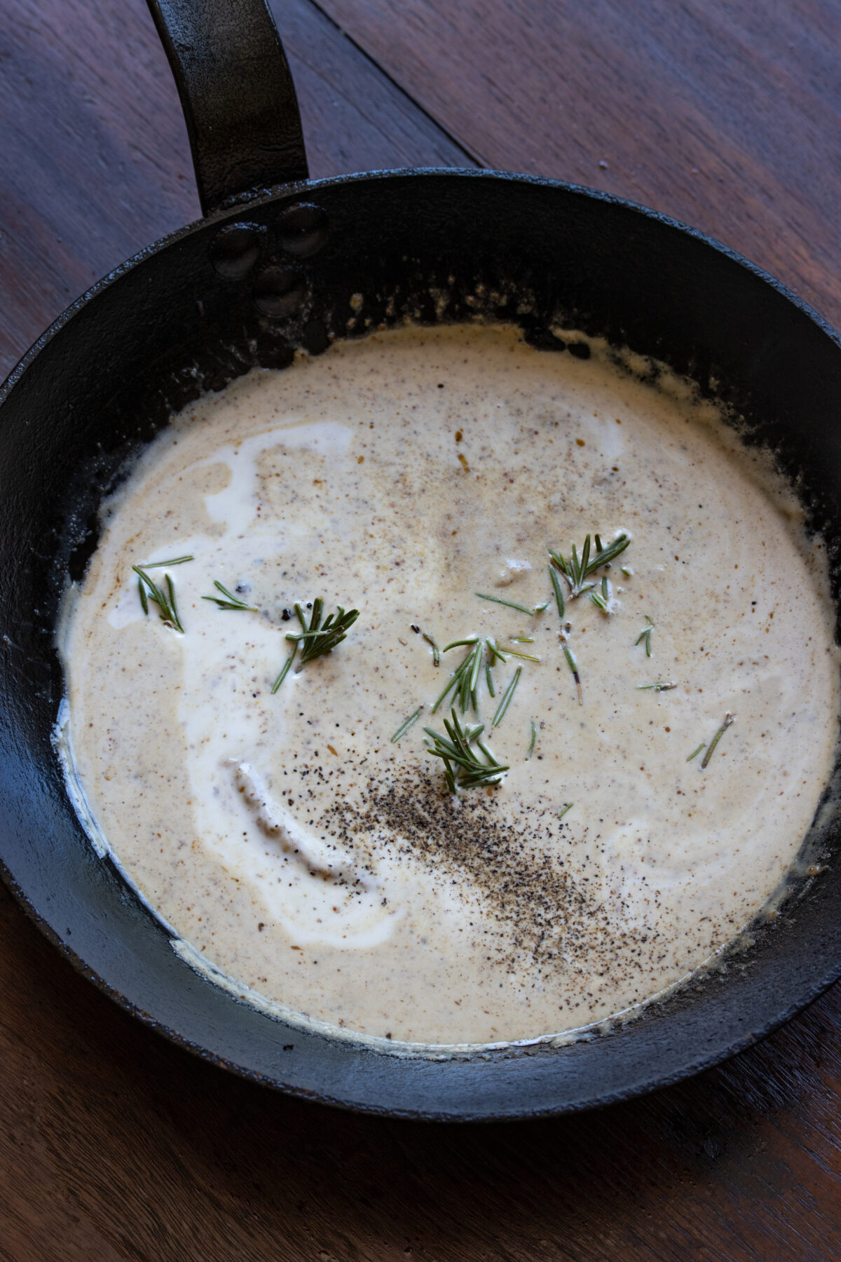 Cream being mixed and rosemary being added to the mustard sauce.