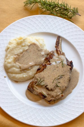 Pan-Seared Pork Chops with Mustard and Rosemary Sauce served in a white plate.